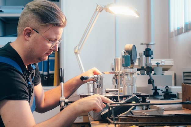 Professionelle Kalibrierung von Manometern und Sensoren Der Arbeiter beschäftigt sich mit der Überprüfung von Kontroll- und Messgeräten am Arbeitsplatz