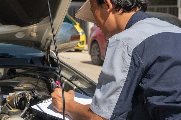 Professionelle Kfz-Reparaturtechniker prüfen den Motor anhand der Checklisten-Dokumente, um sicherzustellen, dass keine Schäden auftreten