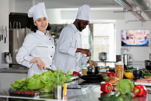 Professionelle Köche in Kochuniformen bereiten frisches Gemüse für ein köstliches Abendessen zu. Gemischtrassige Arbeiter der Lebensmittelindustrie, die in der professionellen Küche des Restaurants stehen. Kochkonzept