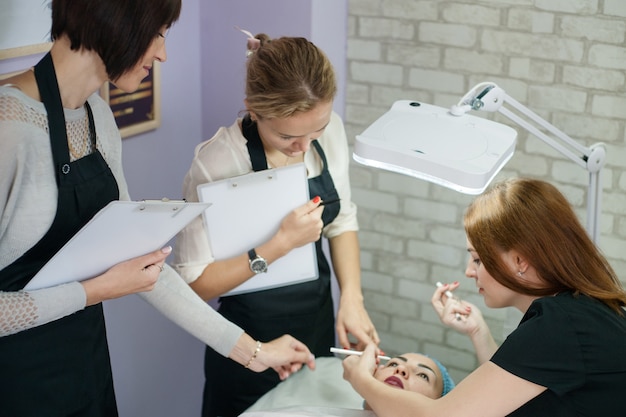 Professionelle Kosmetikkurse. Dauerhaftes Make-up. Weibliche Kosmetikerin, die symmetrische Augenbrauen skizziert.