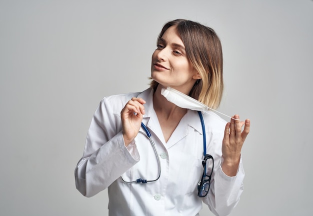 Professionelle Krankenschwester in einem Kleid mit einem Stethoskop und einer medizinischen Maske