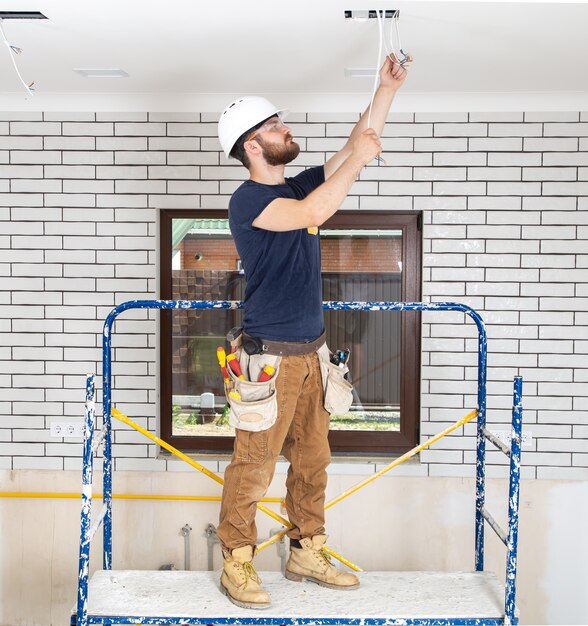 Professionelle Overalls mit Werkzeugen auf dem Hintergrund der Reparaturstelle in voller Länge.