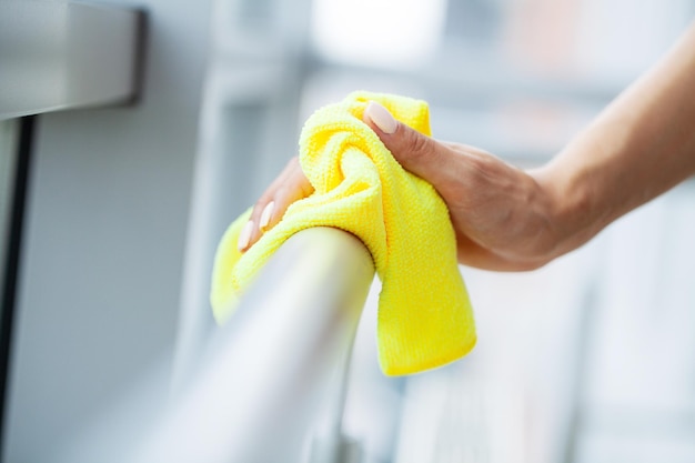 Professionelle Putzfrau reinigt Tisch mit Schwamm und Spray.