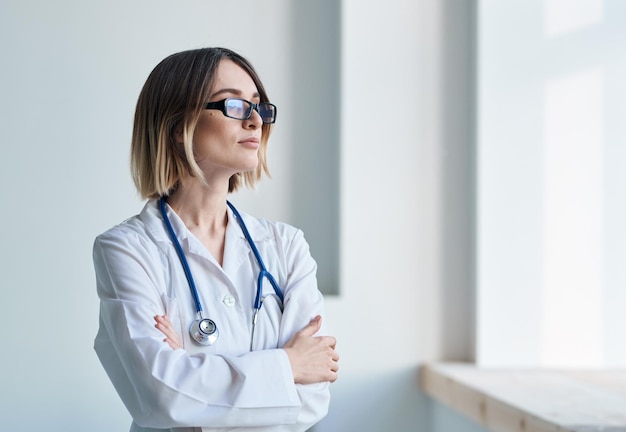 Professionelle Ärztin mit Brille am Fenster und Stethoskop