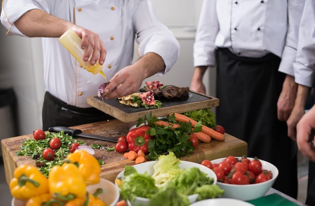 Professionelle Teamköche und Köche bereiten Mahlzeiten in der geschäftigen Hotel- oder Restaurantküche zu