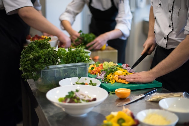 Professionelle Teamköche und Köche bereiten Mahlzeiten in der geschäftigen Hotel- oder Restaurantküche zu