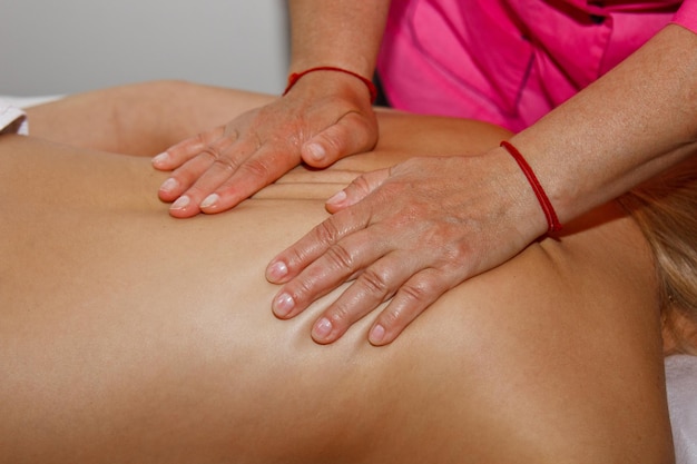 Professionelle therapeutische Rückenmassage. Ärztin massiert Mädchen, die Sportlerin, in einem Massageraum. Verfahren zur Schmerzlinderung im Gesundheitswesen