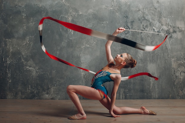 Professionelle Turnerin des jungen Mädchens tanzen rhythmische Gymnastik mit Band im Studio.