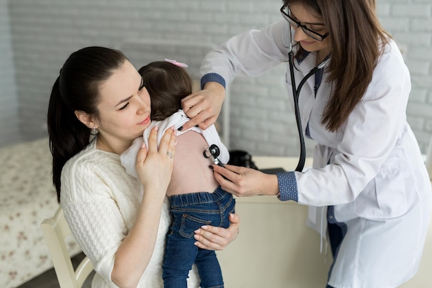 Professioneller allgemeinmedizinischer Kinderarzt in weißem Uniformkleid hört Lungen- und Herzton