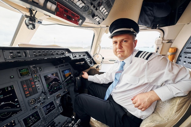 Foto professioneller arbeiter pilot in formeller kleidung sitzt im cockpit und steuert flugzeug