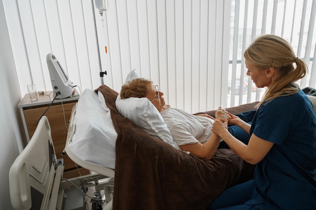 Professioneller Arzt in Uniform untersucht den Patienten während eines Besuchs auf der Krankenstation