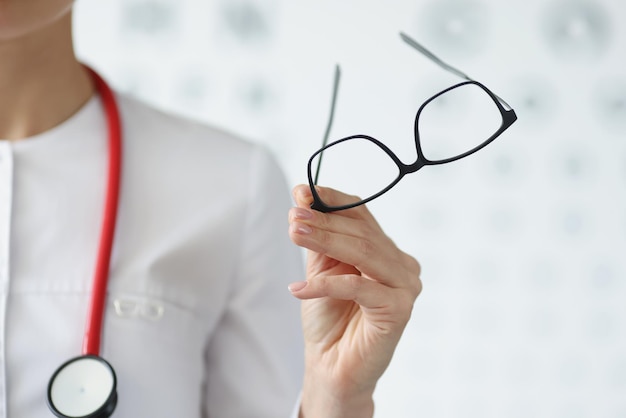 Professioneller Augenarzt hält Brille in schwarzem Rahmen
