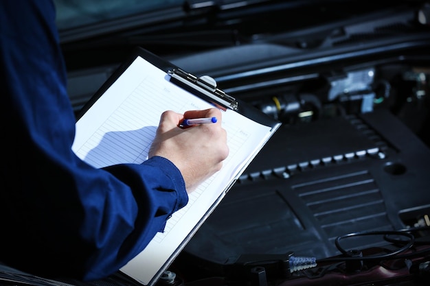 Foto professioneller automechaniker, der in der reparatur von service-nahaufnahmen arbeitet auto-diagnosekonzept