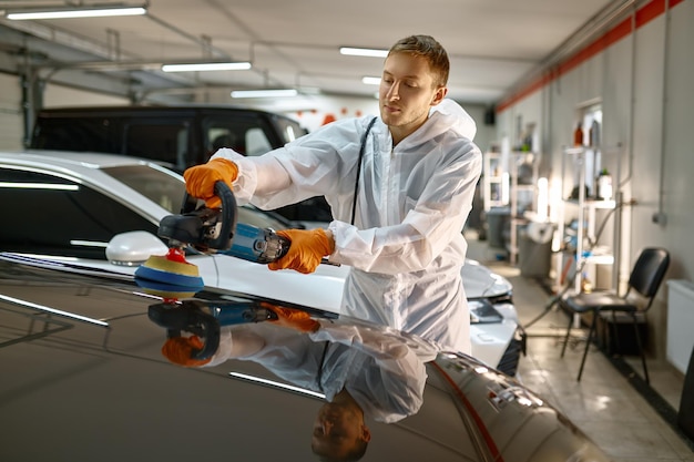 Professioneller Autoservice, männlicher Arbeiter mit Orbitalpolierer, der frisch lackierte Oberfläche poliert