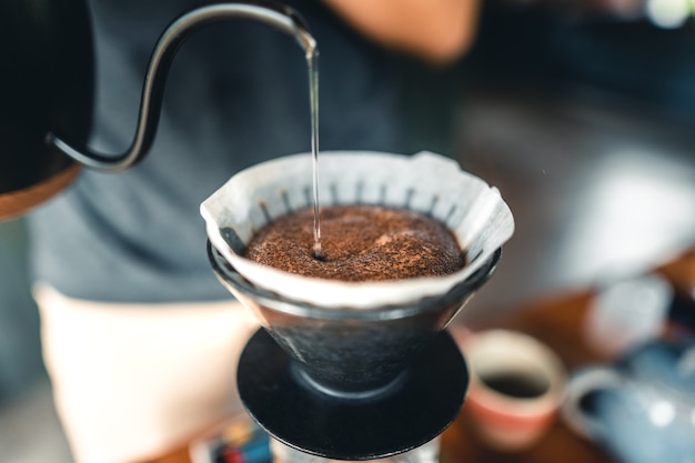 Professioneller Barista, der Kaffee über Kaffeemaschine und Tropfkessel zubereitet drip