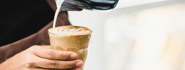 Professioneller Barista, der Latte Art Kaffee macht