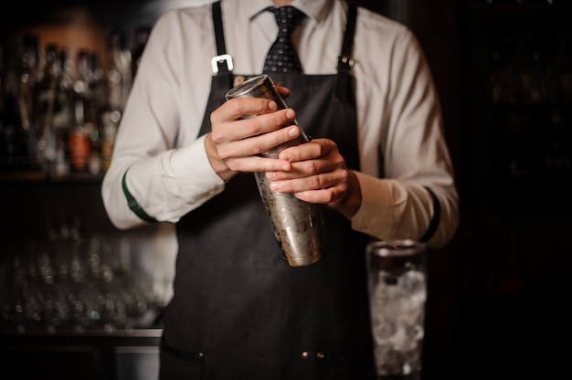 Professioneller Barkeeper, der einen Stahl-Cocktail-Shaker hält