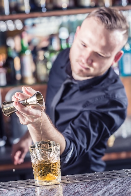 Professioneller Barmann, der altmodisches alkoholisches Cocktailgetränk herstellt.