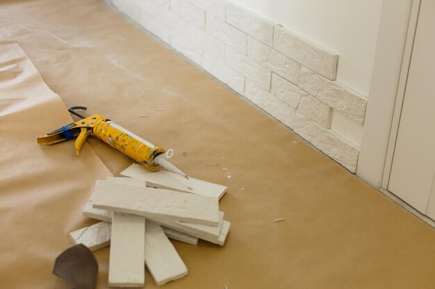 Professioneller Baumeister, der dekorative Fliesen auf Wand klebt. Arbeiter montiert dekorativen Ziegel an der Wand