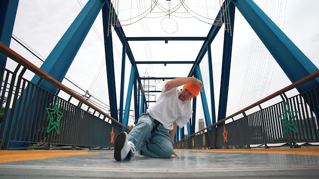 Professioneller Breakdancer führt den Street-Dance-Fußschritt auf der Brücke lebhaft durch