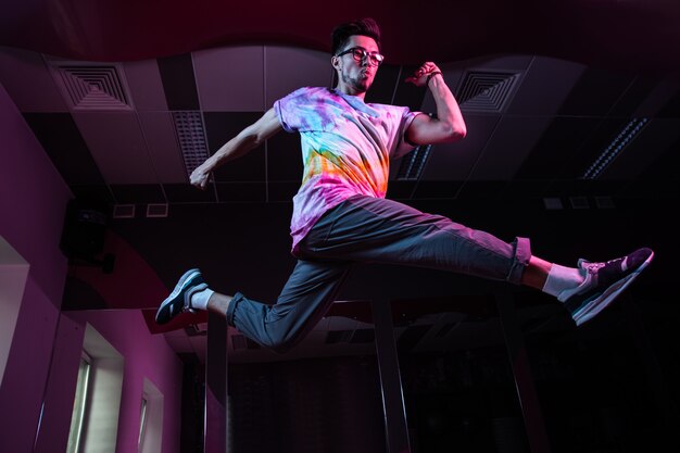 Professioneller Breakdancer in Bewegung, der modernen Hip-Hop-Tanz in rosa Neonlicht übt