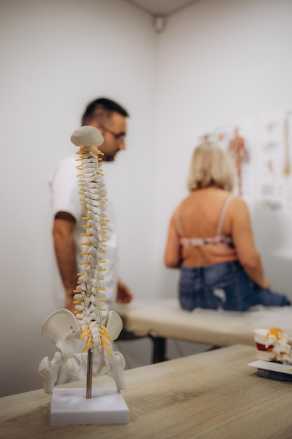 Foto professioneller chiropraktiker, osteopath oder physiotherapeut, der mit älteren weiblichen patienten arbeitet. mann, spezialist für manuelle therapie in einem modernen gesundheitszentrum, massiert den hals und die schultern einer alten dame.