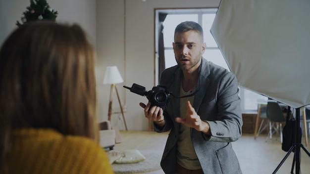 Professioneller Fotograf, der Fotos von Modellen mit einer Digitalkamera macht, die im Fotostudio arbeitet