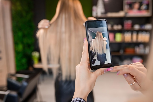 Professioneller Friseur fotografiert Haarverlängerungen von blonden Kunden für Social-Media-Schaufenster