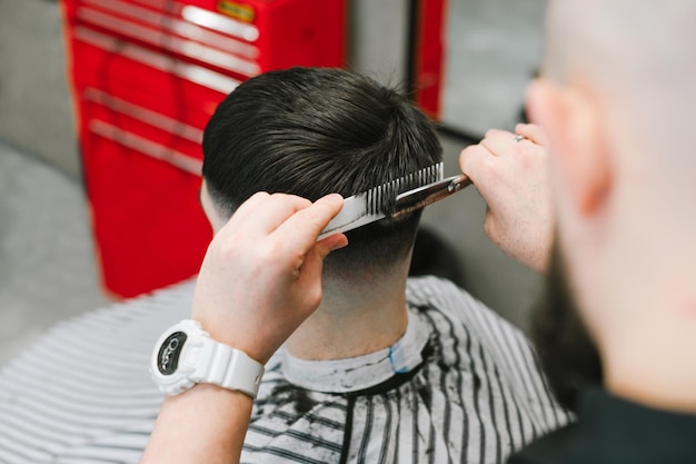 Professioneller Friseur schneidet einen Kunden mit dunklem Haar mit einer Schere und einem Kamm