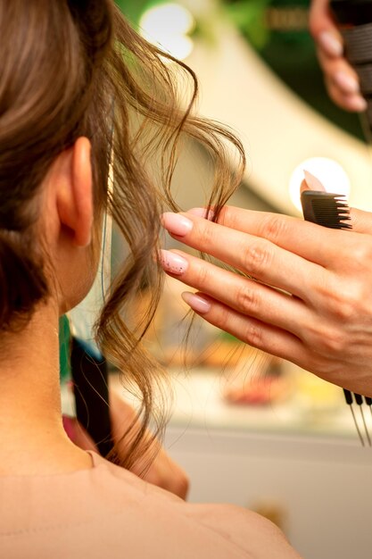 Professioneller Friseur Styling und Fixierung mit Haarspray lange Frau lockiges Haar in einem Schönheitssalon