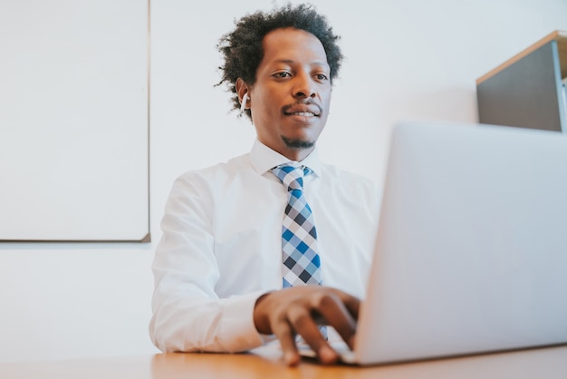 Professioneller Geschäftsmann, der mit seinem Laptop arbeitet, während er im Büro sitzt. Geschäfts- und Erfolgskonzept.