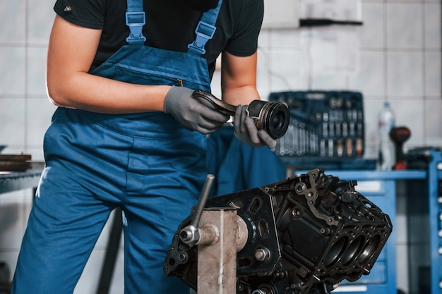 Professioneller Handwerker in der Garage arbeitet mit defektem Automotor