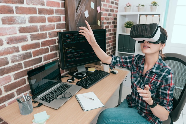 Professioneller junger Computerprogrammierer, der eine VR-Technologiebrille trägt und mit den Händen arbeitet und den Bildschirm berührt, um Codierungsdaten zu organisieren, um ein neues Online-Sicherheitssystem zu entwickeln.