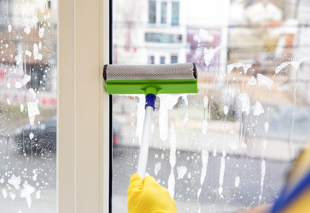 Professioneller junger Hausmeister im einheitlichen Reinigungsfenster drinnen Nahaufnahme