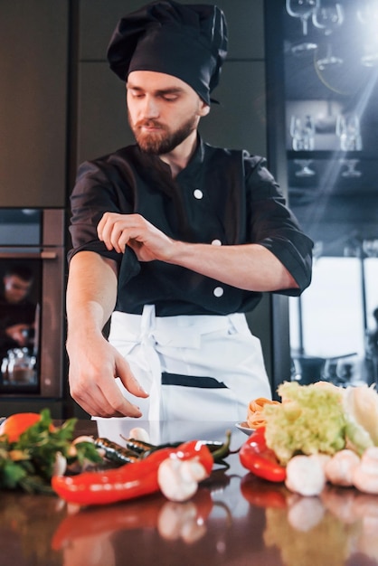 Professioneller junger Koch in Uniform hat einen anstrengenden Tag in der Küche