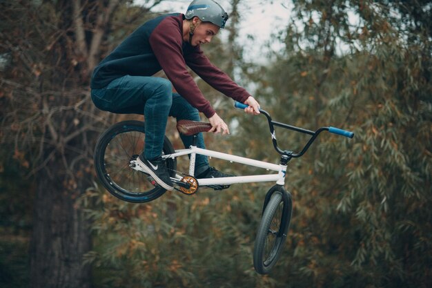 Professioneller junger Sportler-Radfahrer mit BMX-Fahrrad im Skatepark