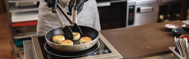 Professioneller Koch bereitet in der Restaurantküche Käsekuchen auf einer Bratpfanne zum Frühstück zu