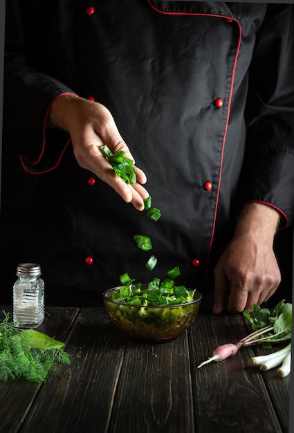 Professioneller Koch bereitet Speisen aus frischem Salat in der Küche zu Kochsalat von den Händen des Küchenchefs Vegetarische Küche