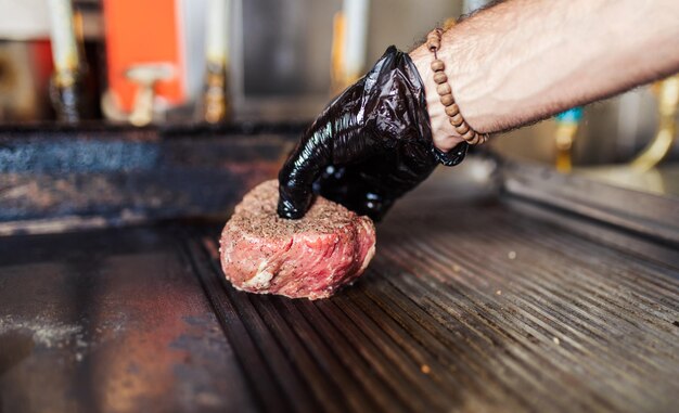 Professioneller Koch in der Restaurantküche, der köstliche Mahlzeiten mit Fleisch und Gemüse zubereitet.