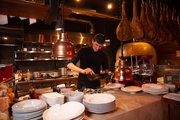 Professioneller Koch in schwarzer Schürze und Mütze, der in der Restaurantküche arbeitet