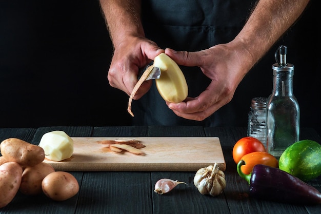 Professioneller Koch schält Kartoffeln für Pommes in einem Restaurant für Kartoffelgerichte