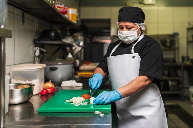 Professioneller Koch schneidet Zwiebeln auf einem Plastikbrett in der Küche des Restaurants