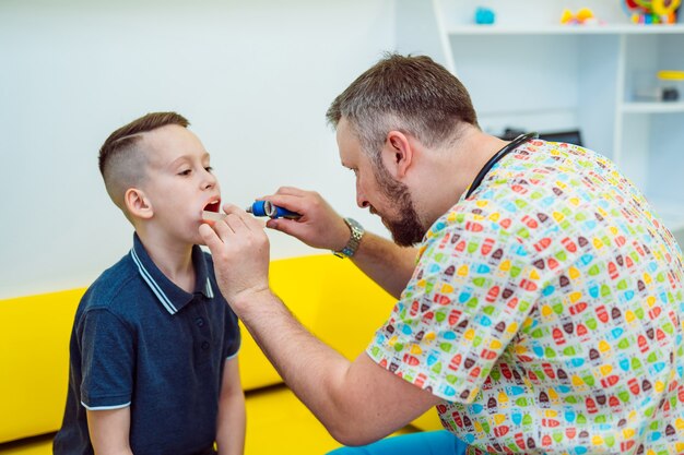 Professioneller männlicher Arzt überprüft Lymphknoten eines kleinen Jungen im medizinischen Zentrum.