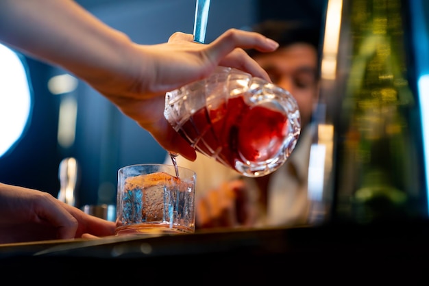 Professioneller männlicher Barkeeper bereitet und serviert Cocktailgetränke für Kunden an der Barbank in einem luxuriösen Nachtclub Barkeeper macht gemischte alkoholische Getränke zur Feier der Feiertage in einer Restaurantbar