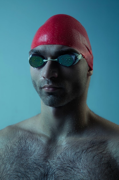 Professioneller männlicher Schwimmer mit Hut und Brille in Bewegung und Action