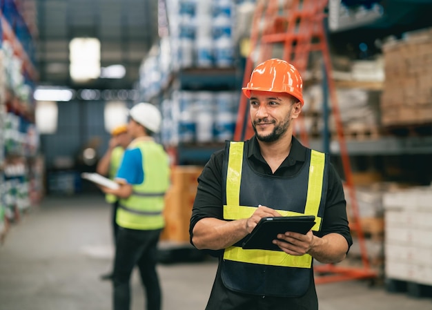 Professioneller Manager-Mann-Mitarbeiter, der Tablet-Check-Lager verwendet, die im Lager arbeiten.