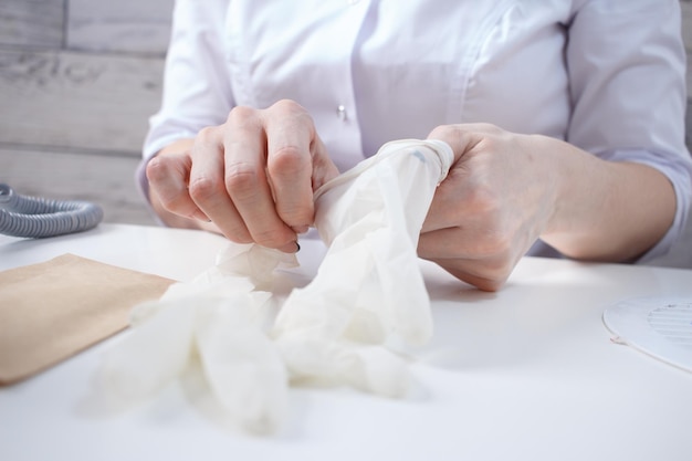 Foto professioneller manikürist zieht weiße medizinische handschuhe an