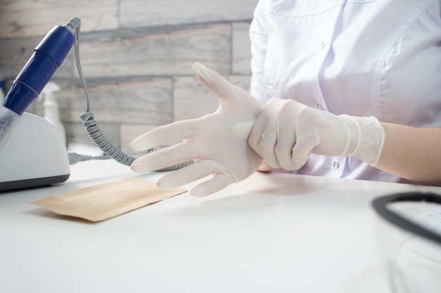 Foto professioneller manikürist zieht weiße medizinische handschuhe an