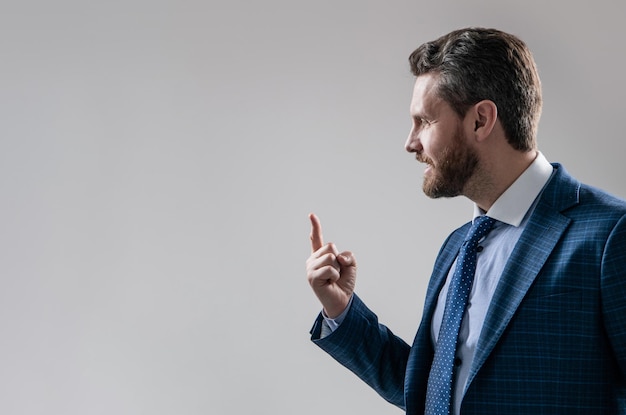 Professioneller Mann im Anzug seitlich halten Finger nach oben grauen Hintergrund Kopie Raum Idee zeigen