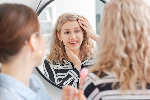 Professioneller Maskenbildner, der mit junger Frau im Salon arbeitet